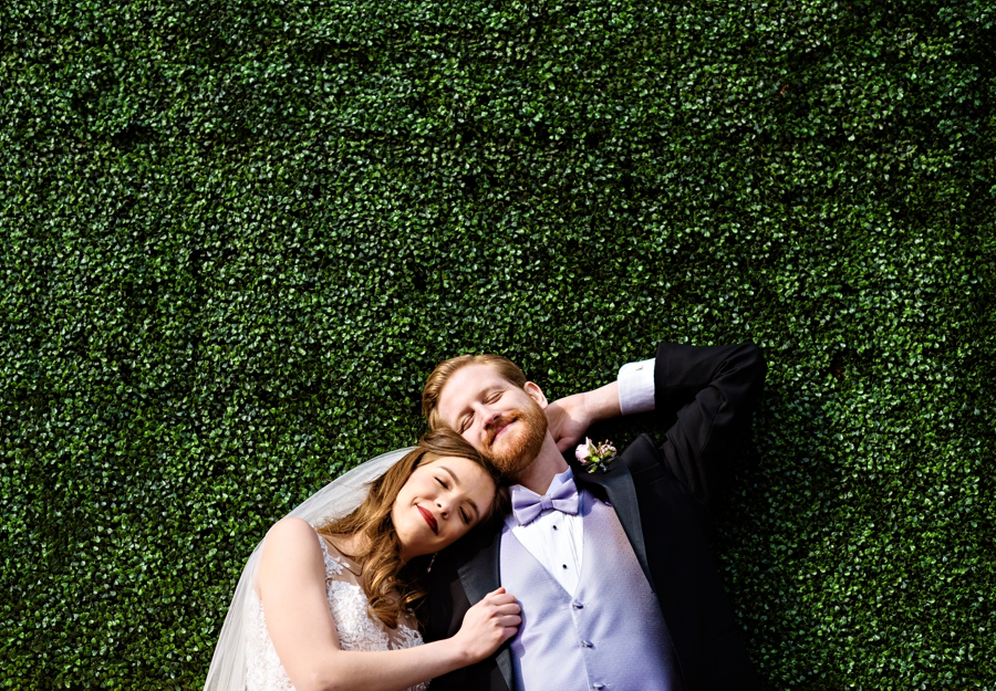 A newly married couple soak up the sun laying in the grass outside of the Water Works in Philadelphia at their wedding.
